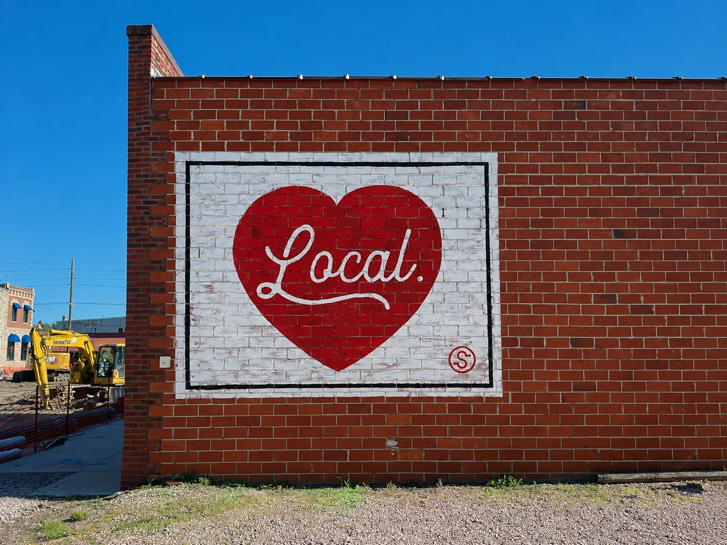Red heart-shaped Local mural painted on a white brick panel at a Sandhills State Bank property