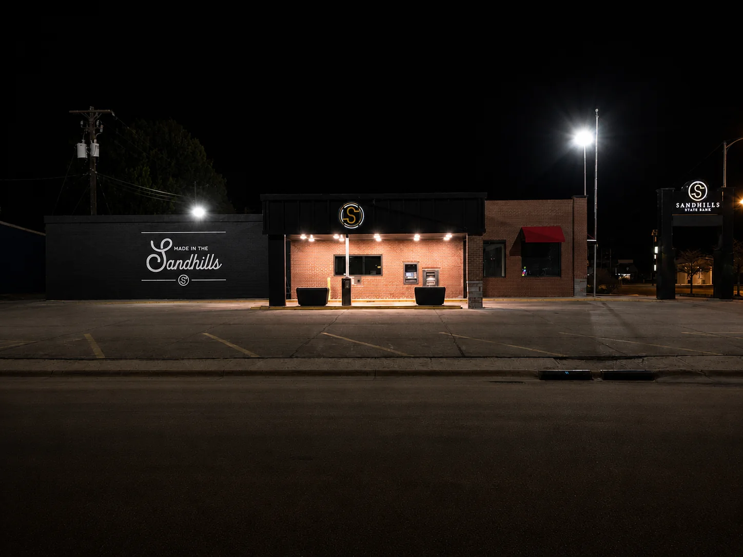 Wide nighttime view of a Sandhills State Bank branch in Ogallala with painted signage across two exterior walls