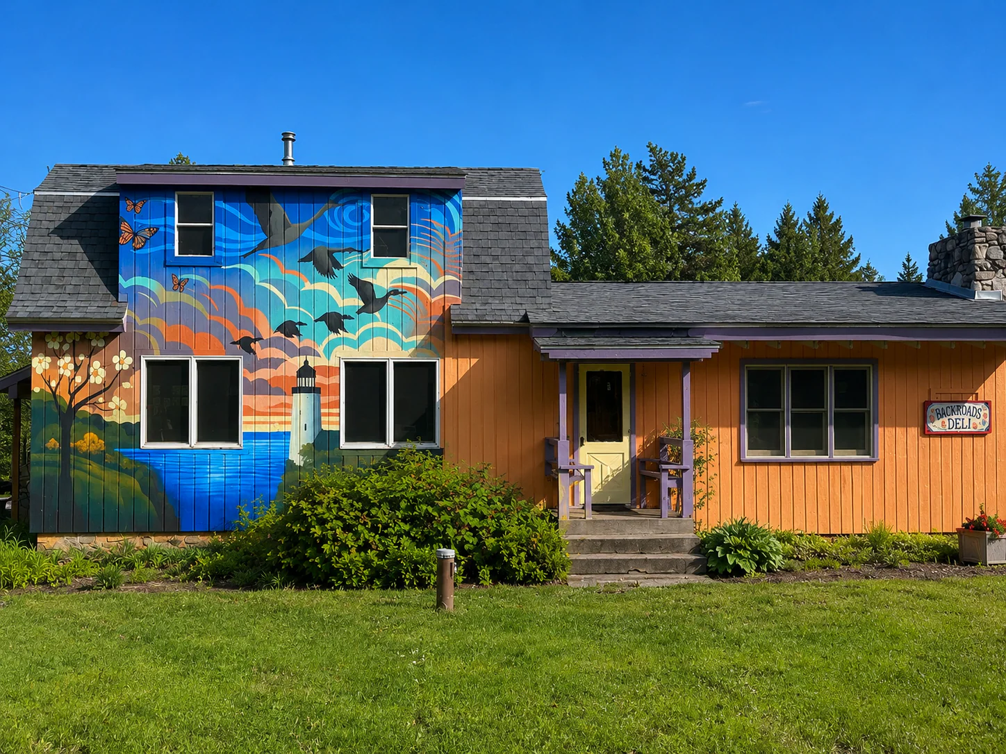 Building-scale exterior mural with migratory birds, butterflies, water, and a layered Door County landscape
