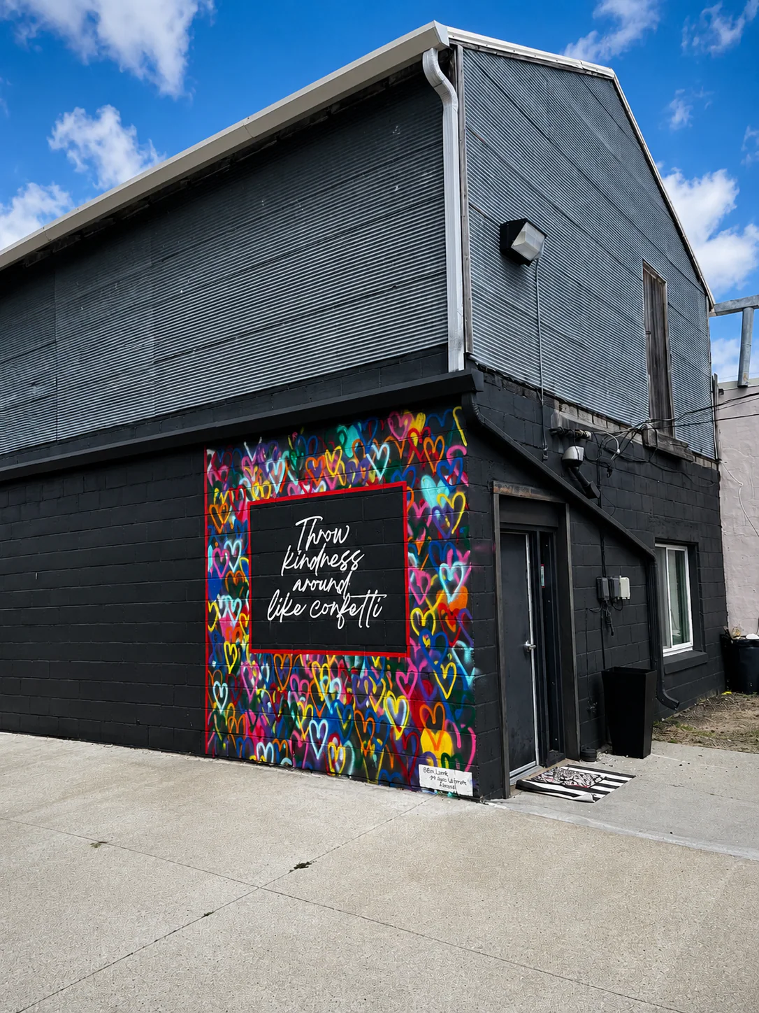 Vertical streetscape view of the Throw Kindness mural on the corner of Valentine Dance Studio