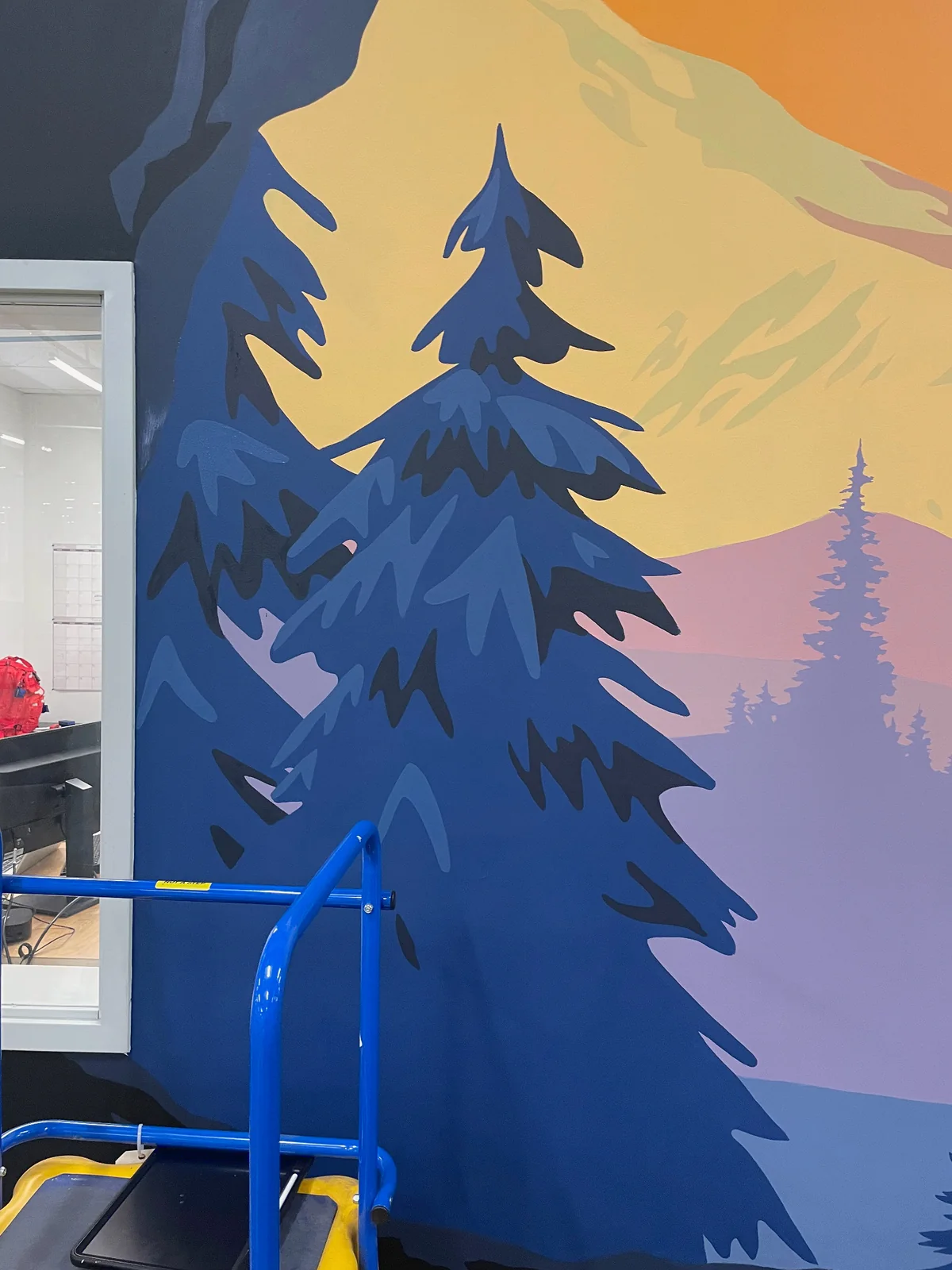 Painted detail of layered evergreen trees and pastel mountains in the Wolf Den mural