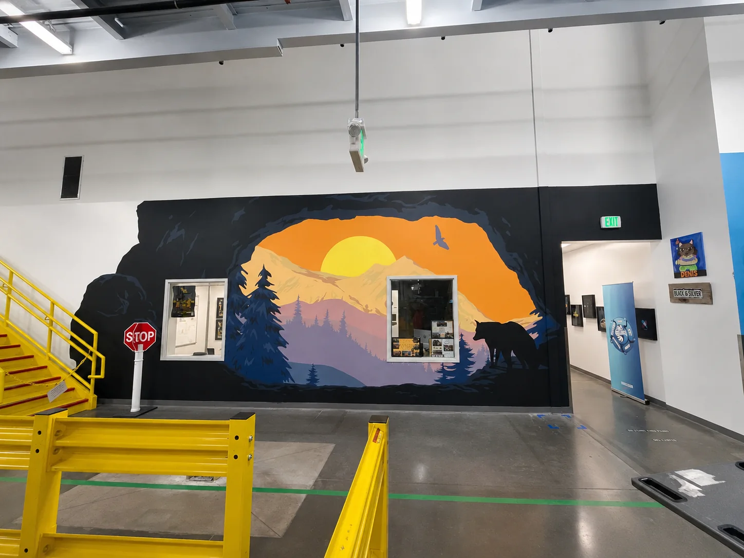 Amazon workplace interior with a mountain and wolf mural framed by a dark cavern-like silhouette