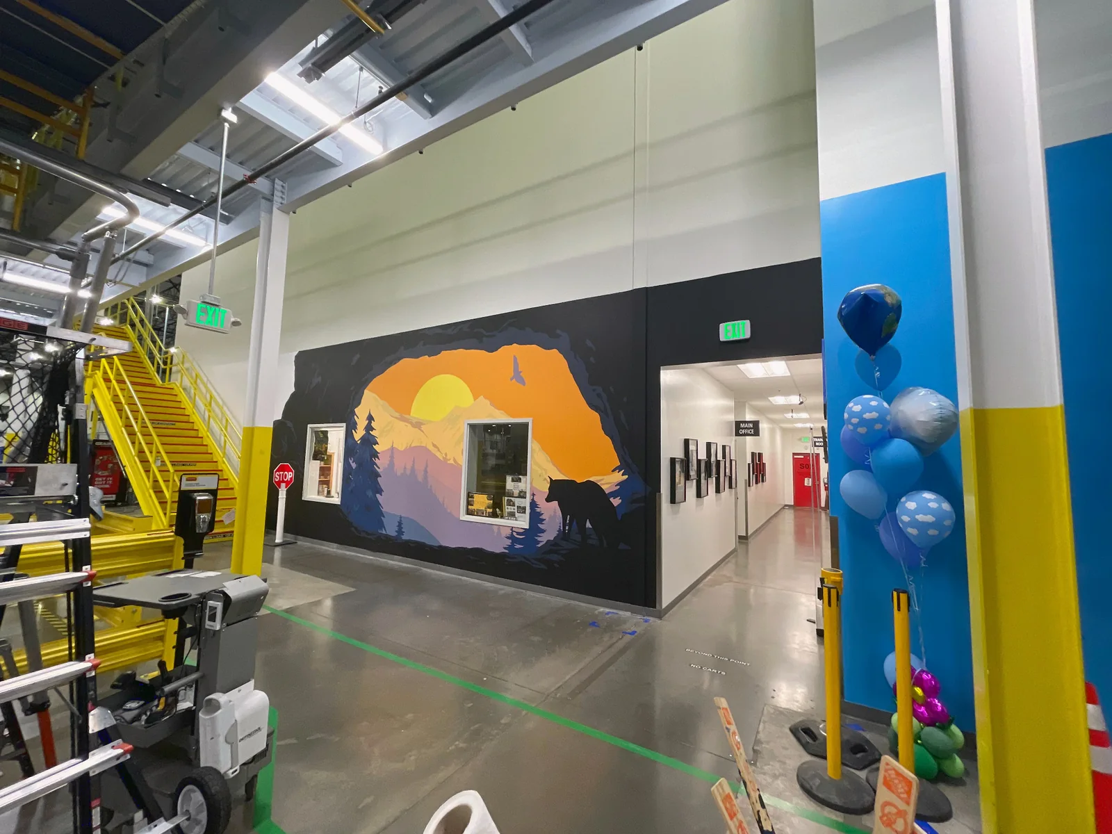 Wide view of the Wolf Den mural within an active Amazon industrial workplace